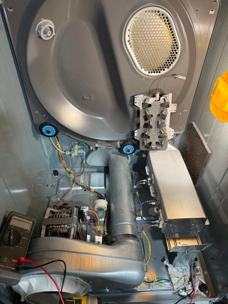 Dryer interior with heating element and ductwork during repair